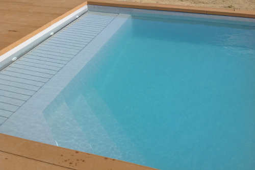 Copertura della piscina a tapparella di colore grigio e carabottino immerso a costituire una spiaggia di circa 1 m